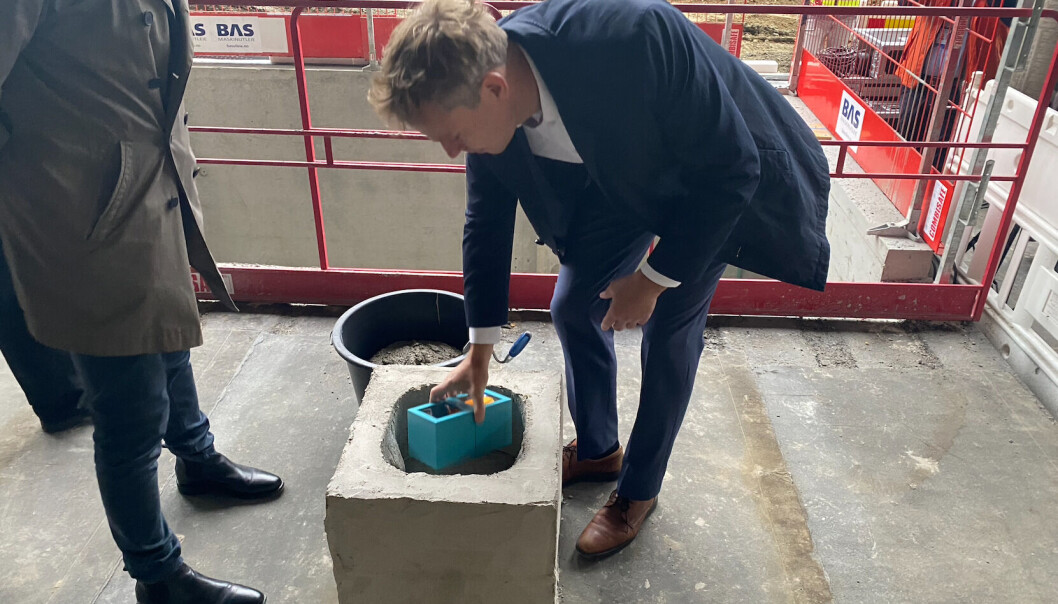 Ministeren legger en tidskapsel ned i det som blir grunnsteinen i Helgasetr-bygget. Ministeren legger en tidskapsel ned i det som blir grunnsteinen i Helgasetr-bygget.