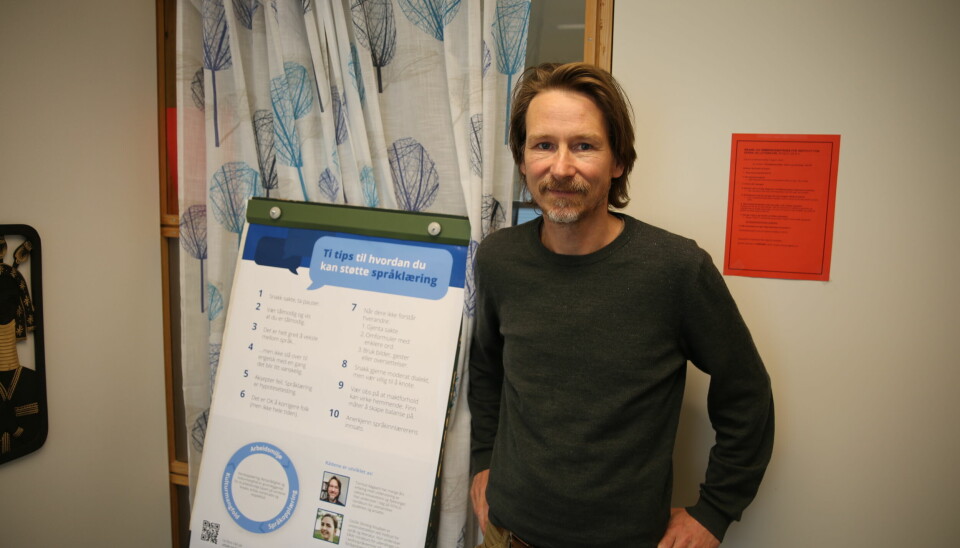 Tormod Aagaard ein plakat med ti tips til korleis ein kan støtte språklæring på kontoret sitt på Dragvoll.