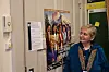 Eldre kvinne ser mot en fargerik plakat på en kontordør i en universitetsgang.