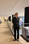 Kelsey Martin står i en moderne, lyst innredet bygning med glassrekkverk og sittegruppe.