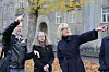 En gruppe personer står ute på en campus og peker mot bygninger.